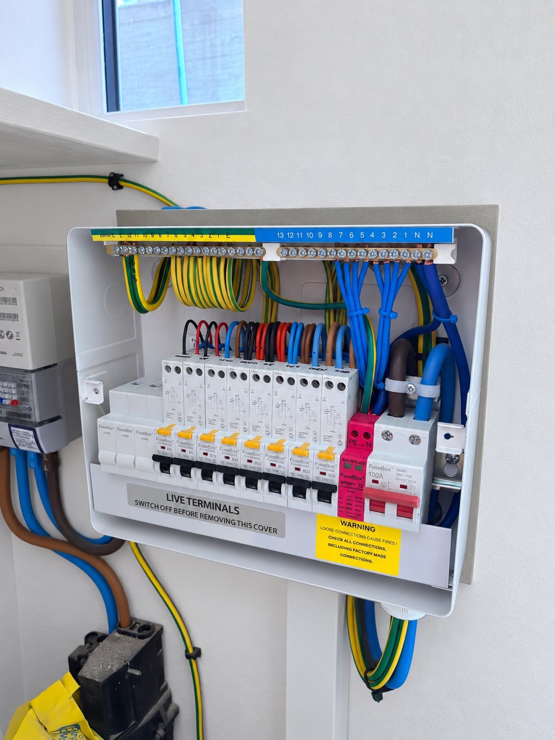 Flush mounted consumer unit mid installation with RCBOs, surge protection and neatly dressed cables